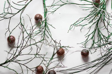 Yeşil dallar beyaz arka planda yatar. Ve yakınlarda mumlar ve fenerler var.