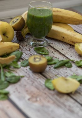 Bir bardak kivi, ıspanak ve elma püresi. Sağlık içeceği. Elma, keten tohumu, ıspanak, kivi, muz yakınlarda..