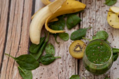 Bir bardak kivi, ıspanak ve elma püresi. Sağlık içeceği. Elma, keten tohumu, ıspanak, kivi, muz yakınlarda..