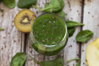 Bir bardak kivi, ıspanak ve elma püresi. Sağlık içeceği. Elma, keten tohumu, ıspanak, kivi, muz yakınlarda..