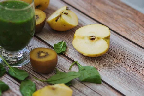 A glass of kiwi, spinach and apple smoothie. Health drink. Apples, flax seeds, spinach, kiwi, bananas lie nearby.