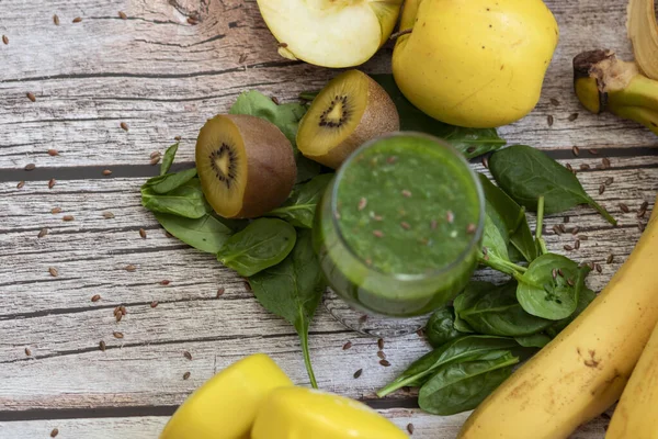 Bir bardak kivi, ıspanak ve elma püresi. Sağlık içeceği. Elma, keten tohumu, ıspanak, kivi, muz yakınlarda..