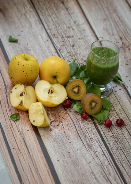 A glass of kiwi, spinach and apple smoothie. Health drink. Apples, flax seeds, spinach, kiwi, bananas lie nearby.