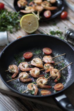 Tavada karides şiş, yağda kızartılmış ve baharatlı. Bunların hepsi masanın üzerinde. Yakınlarda bir tabak karides şalgamı var.