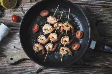 Tavada karides şiş, yağda kızartılmış ve baharatlı. Bunların hepsi masanın üzerinde. Yakınlarda bir tabak karides şalgamı var.