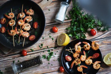 Tavada karides şiş, yağda kızartılmış ve baharatlı. Bunların hepsi masanın üzerinde. Yakınlarda bir tabak karides şalgamı var.