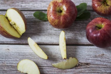 Büyük kırmızı elmalar ahşap bir masada yatar.