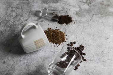 Anında kahve, kahve çekirdekleri ve öğütülmüş kahve. Hepsi gri arka planda.