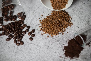 Anında kahve, kahve çekirdekleri ve öğütülmüş kahve. Hepsi gri arka planda.
