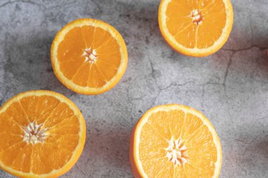 Portakal yarımları masanın üstünde. Gri ve beyaz bir arkaplanda.