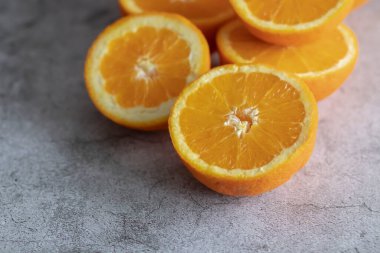 Portakal yarımları masanın üstünde. Gri ve beyaz bir arkaplanda.