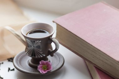 Pencerenin yanında güzel bir kahve fincanı var. Yakınlarda da kitaplar var.