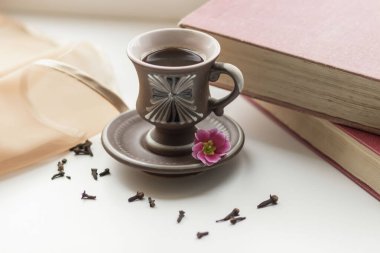 Pencerenin yanında güzel bir kahve fincanı var. Yakınlarda da kitaplar var.