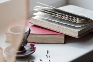 Pencerenin yanında güzel bir kahve fincanı var. Yakınlarda da kitaplar var.