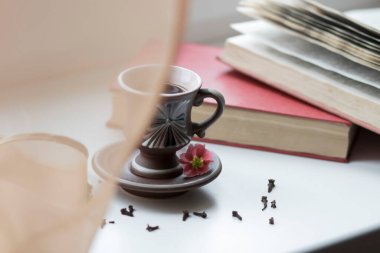 Pencerenin yanında güzel bir kahve fincanı var. Yakınlarda da kitaplar var.