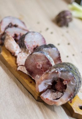 Fish. There is a raw fish cut into pieces on the kitchen board. And the whole thing.