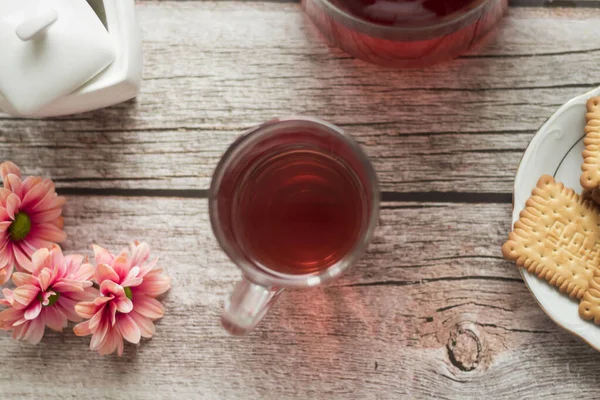 Sabah çayı masadadır. Yakınlarda çiçekler ve bisküviler var..