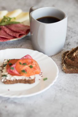 Kahve ve sandviçle hazırlanmış kahvaltı. Bunların hepsi gri bir arka planda