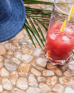 Yaz geçmişleri. Çakıl taşı. Çakıl taşları, şapkalar ve palmiye yaprakları, bir bardak meyve suyu