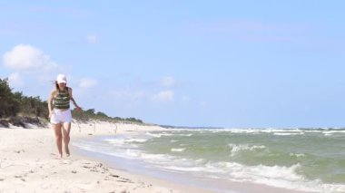 Genç kız sahilde yürüyor.