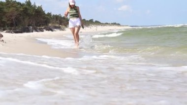 Genç kız sahilde yürüyor.