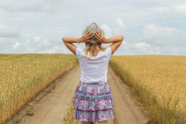Genç bir kız buğday tarlasında yürüyor