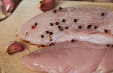 Çiğ hindi göğsü. Tahta tahtaya uzan. Tüm bunlar bir ağaç arka planında.