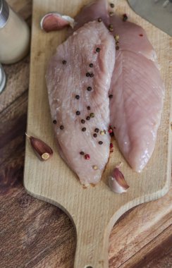 Çiğ hindi göğsü. Tahta tahtaya uzan. Tüm bunlar bir ağaç arka planında.