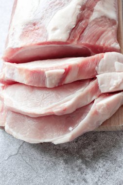 Gri arka planda bir parça çiğ domuz. Taze et pişmeye hazır. Yukarıdan görünüm
