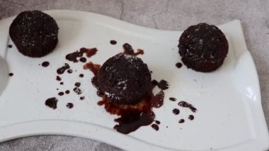 Beyaz tabakta çikolatalı kek. İçi siyah çikolata dolu.