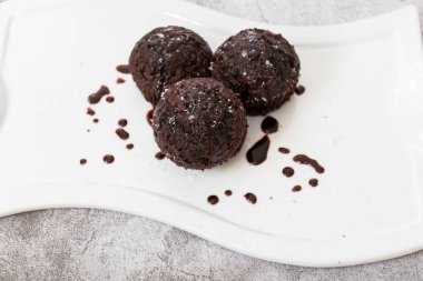 Beyaz tabakta çikolatalı kek. Üstüne çikolata ve hindistan cevizi serpiştirilmiş. Ev yapımı yumuşacık ve sulu çikolatalı kekler. Gri bir arkaplanda