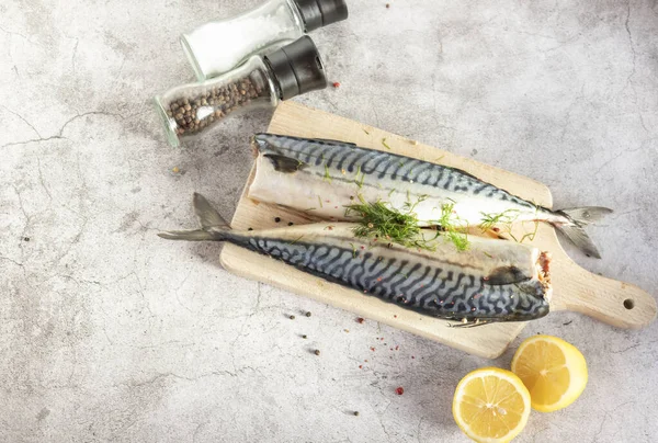 Fresh raw mackerel fish. On a gray background. Raw fish with lemon and dressings