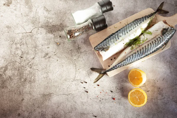 Fresh raw mackerel fish. On a gray background. Raw fish with lemon and dressings