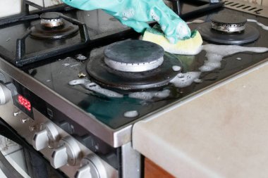 Mutfak temizliği. Yeşil koruyucu lastik eldivenli kadın mutfak mobilyalarını temizliyor.