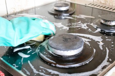 Mutfak temizliği. Yeşil koruyucu lastik eldivenli kadın mutfak mobilyalarını temizliyor.