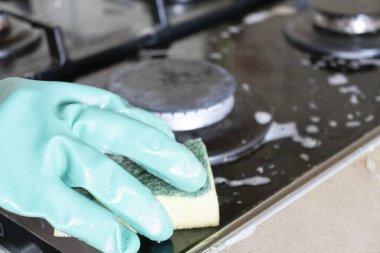 Mutfak temizliği. Yeşil koruyucu lastik eldivenli kadın mutfak mobilyalarını temizliyor.