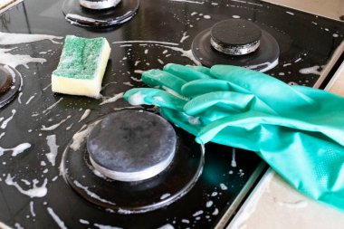 Mutfak temizliği. Yeşil koruyucu lastik eldivenli kadın mutfak mobilyalarını temizliyor.