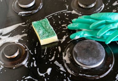 Mutfak temizliği. Yeşil koruyucu lastik eldivenli kadın mutfak mobilyalarını temizliyor.