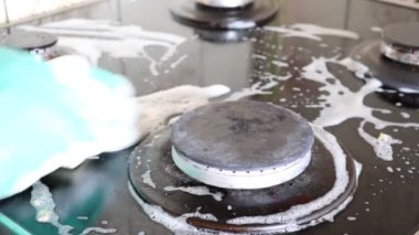 Mutfak temizliği. Yeşil koruyucu lastik eldivenli kadın mutfak mobilyalarını temizliyor.