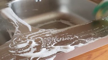 Mutfak temizliği. Yeşil koruyucu lastik eldivenli kadın mutfak mobilyalarını temizliyor.