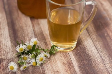 Ahşap arka planda papatya çayı. Bir fincan papatyanın yanında.