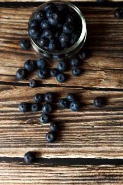 Kırsal ahşap bir yüzeye serpilmiş taze yaban mersini. Yumuşak ışıklandırma ve bulanık bir arka plan ile natürmort yaşam kompozisyonu. Sağlıklı yeme, organik gıda ve doğal tazelik kavramı.