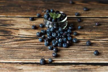 Kırsal ahşap bir yüzeye serpilmiş taze yaban mersini. Yumuşak ışıklandırma ve bulanık bir arka plan ile natürmort yaşam kompozisyonu. Sağlıklı yeme, organik gıda ve doğal tazelik kavramı.