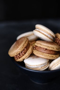 Koyu arkaplanda makaronlar, renkli Fransız kurabiyeleri. Kurabiyeler. Vanilyalı ve çikolatalı tatlı. Sağlıklı vejetaryen şeker yok. 8 Mart - Uluslararası Kadınlar Günü