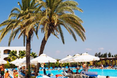 İnsanlar yazın palmiye ağaçlarının altındaki havuzda dinlenirler..