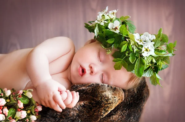巣で彼の頭に花輪を捧げるで眠っている赤ちゃん ロイヤリティフリーのストック画像