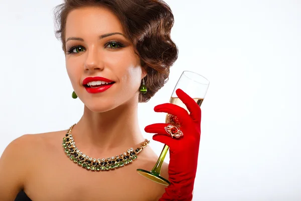 Sexig modell kvinna med glas champagne i röda handskar och trendiga smycken — Stockfoto