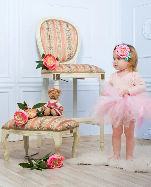 Malá holčička, oblečený jako baletka v tutu stojící vedle růžové růže. — Stock fotografie