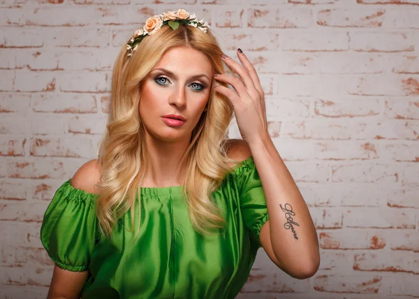 Girl in floral wreath and with a tattoo on his arm. — Stock Photo, Image