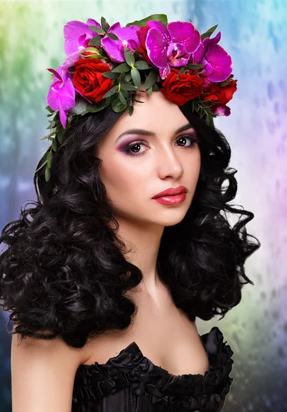 Menina bonita com uma grinalda de orquídeas na cabeça. Mulher glamorosa em espartilho de couro preto. cabelo encaracolado preto longo Isolado no branco — Fotografia de Stock